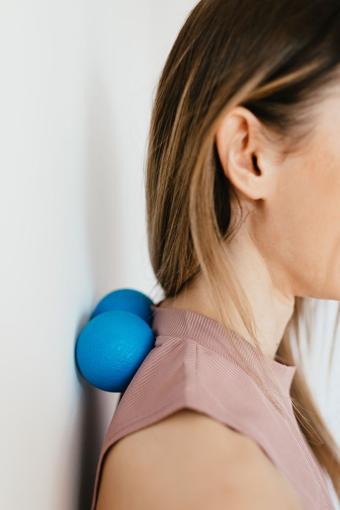 Services 4 Side view crop anonymous lady leaning on balls against wall to massage stiff neck muscles and relieve spinal pain