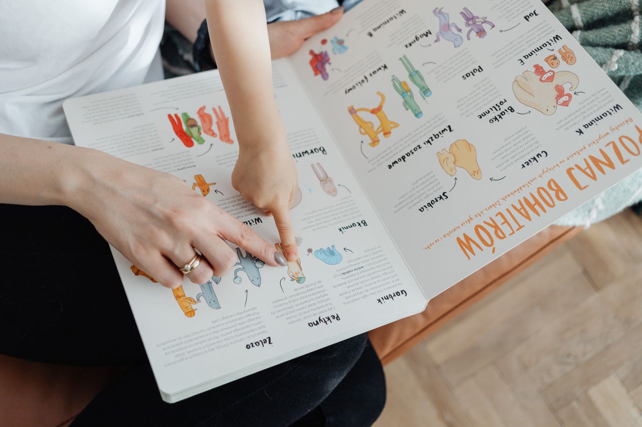 A child and adult engaging with an educational book, pointing to illustrations.